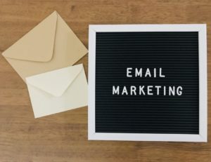 email marketing written on letter board with white and tan envelope