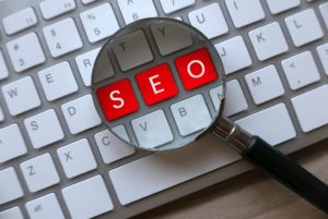 SEO highlighted in red letters with magnifying glass on keyboard