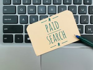 paid search written on piece of paper with pen sitting on top of keyboard