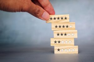 person stacking little wooden blocks with one to five star rating