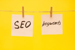 yellow background with two close pins holding light colored post-its that say SEO and Keywords