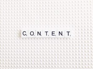 white scrabble background with white scrabble tiles with black writing that say content