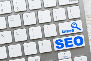 whit keyboard with SEO and Keywords and a magnifying glass written in blue on keys