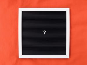 black and white letter board on orange background with white question mark in the middle